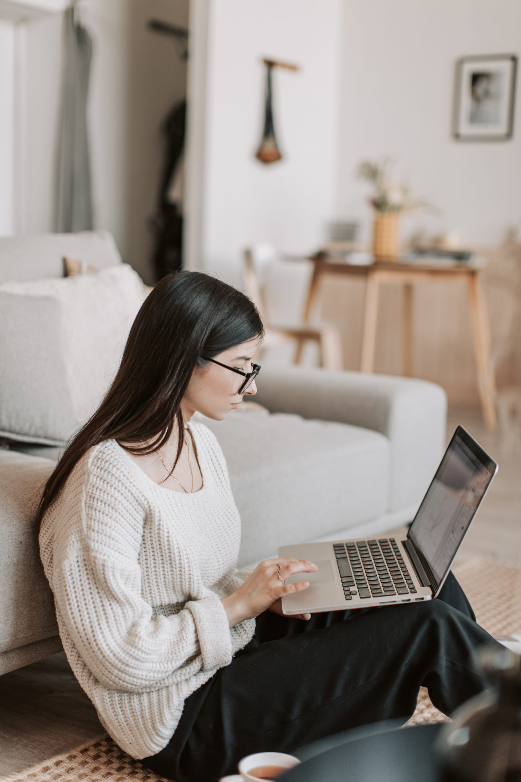 Canva - Concentrated woman using laptop on floor in living room